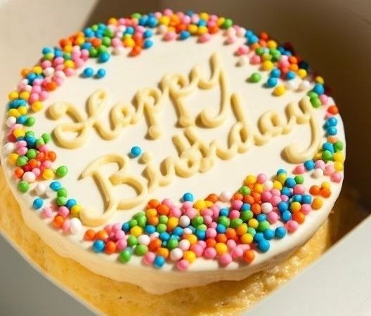 Birthday cake with 'Happy Birthday' icing and colorful sprinkles on top.