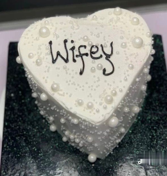 Heart-shaped white cake with pearls and 'Wifey' written on top.