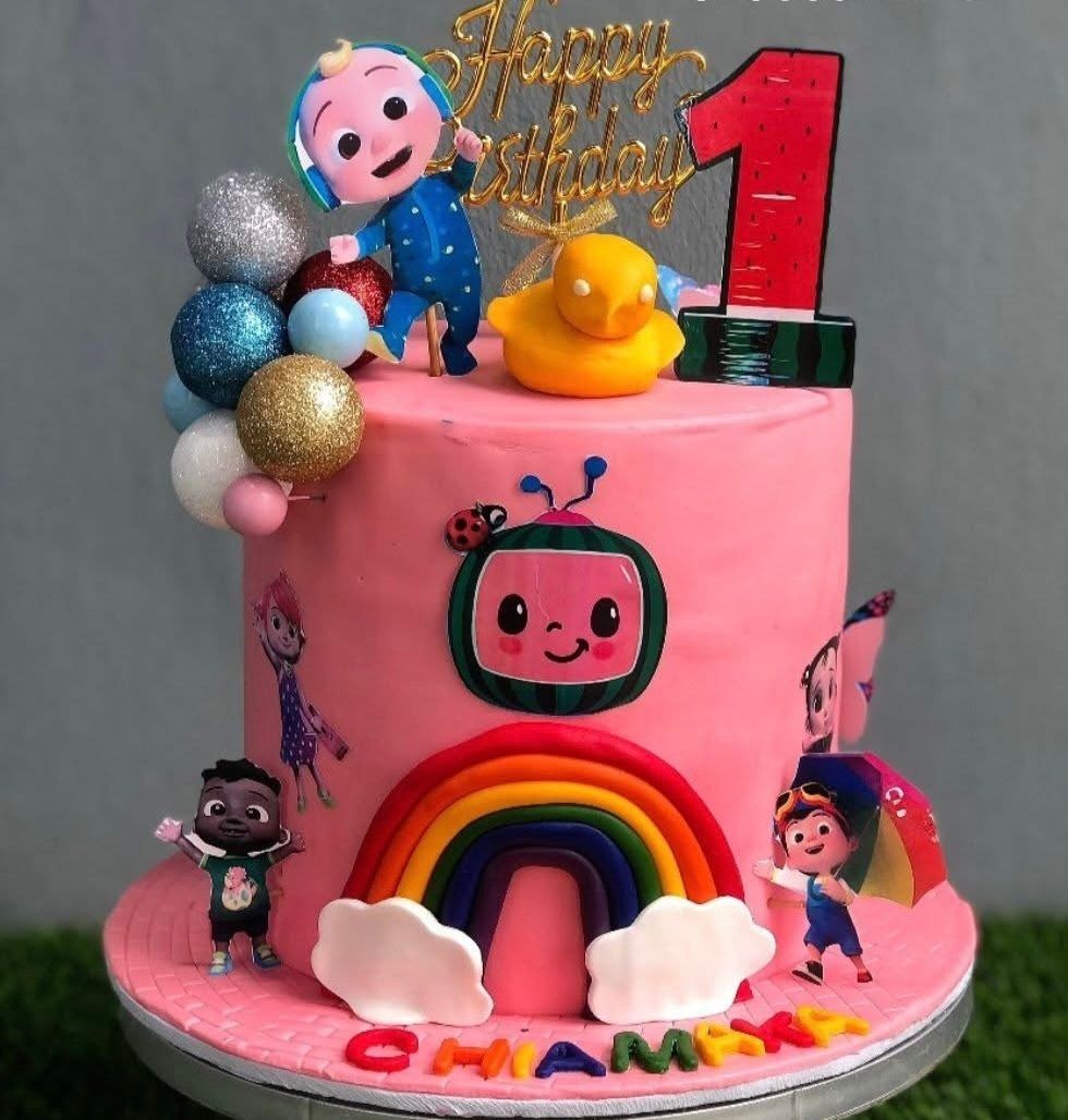 Colorful birthday cake with cartoon characters, rainbow decoration, and a 'Happy Birthday' topper.