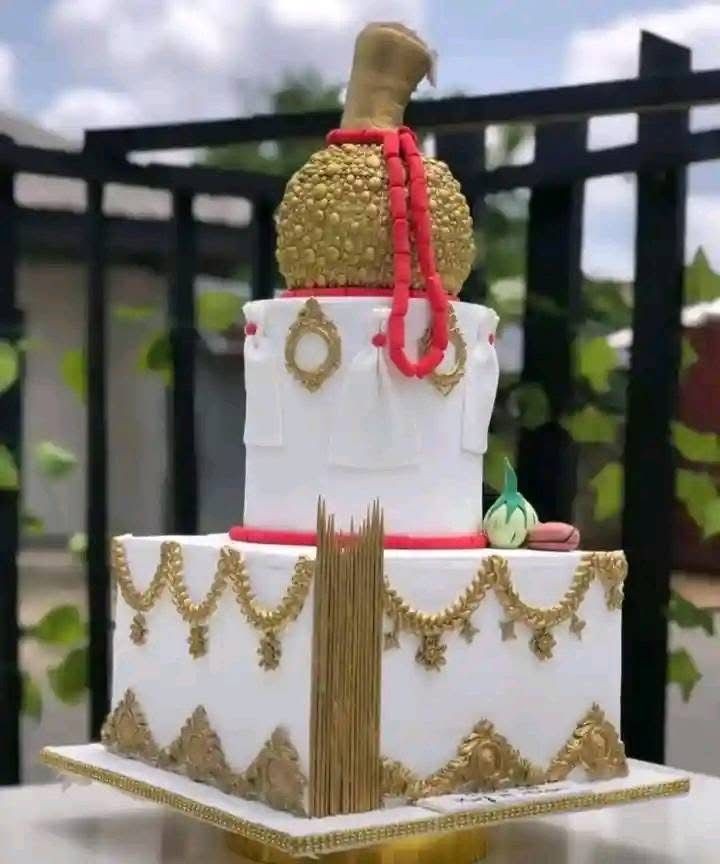 Elaborate multi-tier cake with gold and red decorations, resembling traditional ceremonial attire.