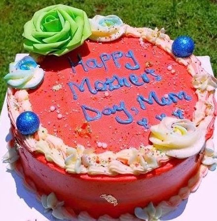 Red Mother's Day cake with white frosting and green flower decoration.