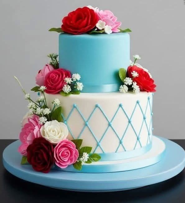 Two-tier blue and white cake decorated with red and pink roses and small white flowers.