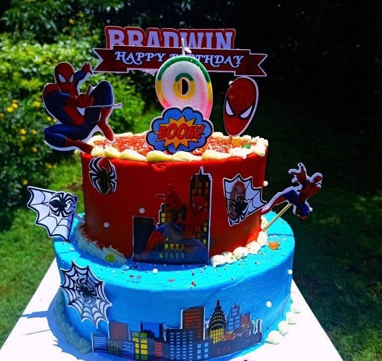 Spiderman-themed birthday cake with cityscape decorations and figures.