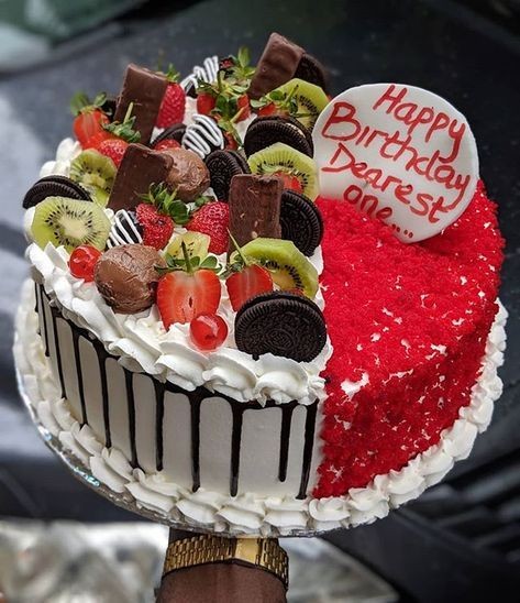 Decorative birthday cake with fruits, chocolates, and a message on top.